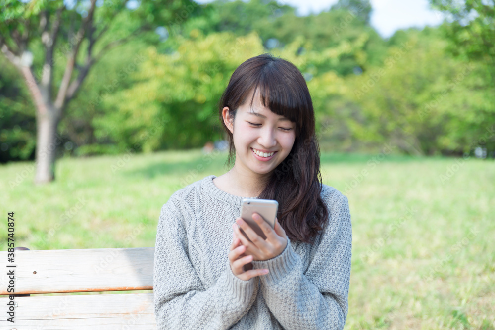 若い女性　スマホ　公園